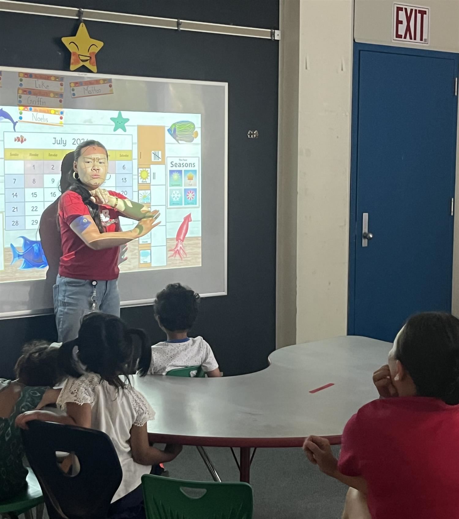 Teacher in front of board with students watching